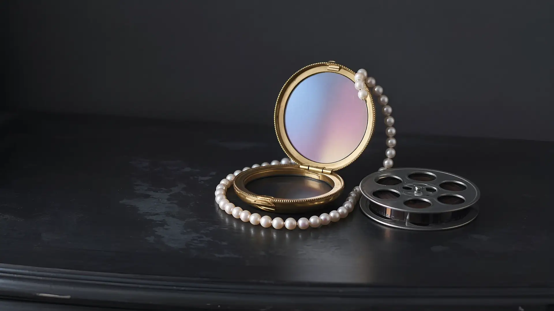 Old Hollywood glamour still life of a vintage powder compact, pearls and a film reel on a vanity in soft pastel light